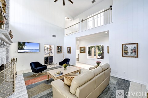 A living room with a beige couch, a blue chair, and a television on the wall.