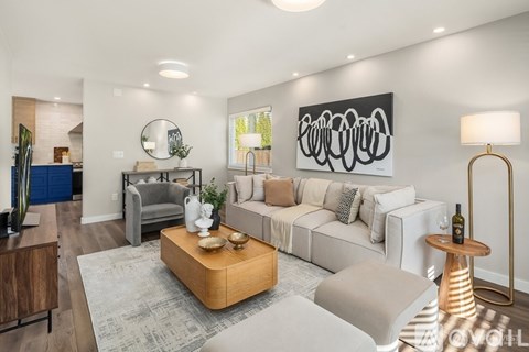 A modern living room with a large white sofa, a wooden coffee table, and a large abstract painting on the wall.