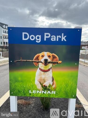 A sign for a dog park with a dog holding a stick in its mouth.