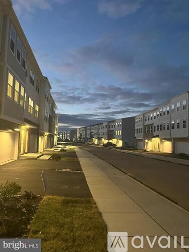 A street view of a residential area with buildings on either side and a cloudy sky.