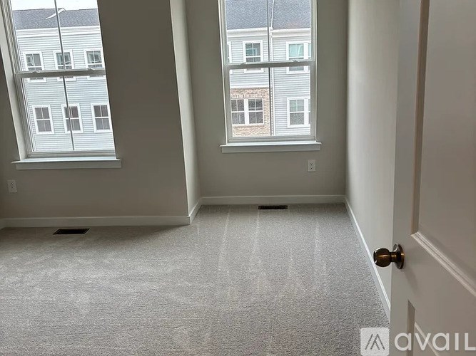 A room with a carpeted floor and two windows.