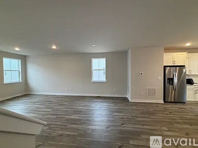 A spacious empty room with a wooden floor and a window.