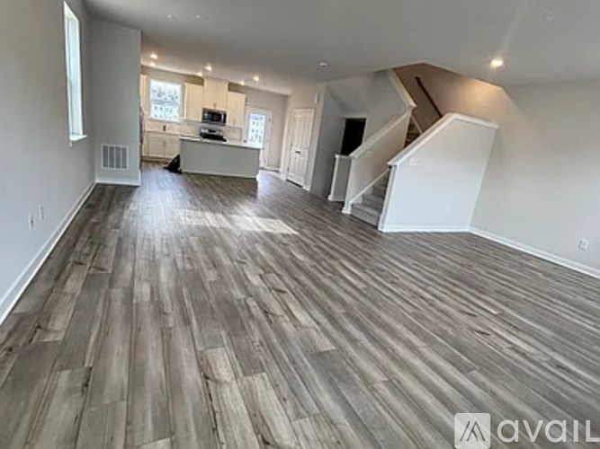 A spacious room with wooden flooring and a staircase leading to another level.