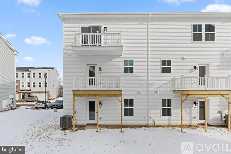 A white two-story apartment building with balconies and a parking lot in front.