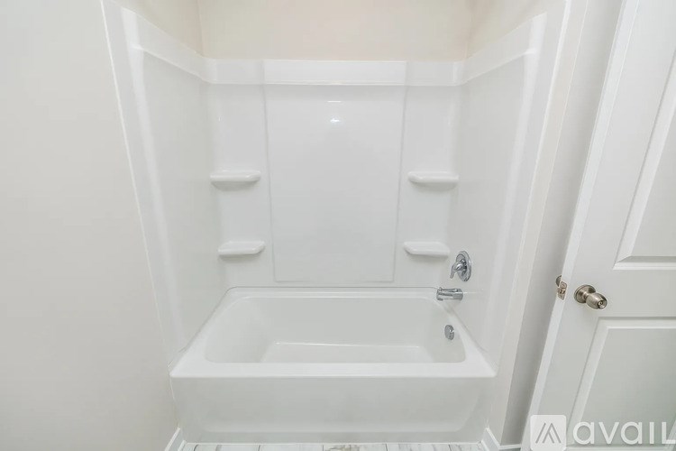 A white bathroom with a tub and a door.