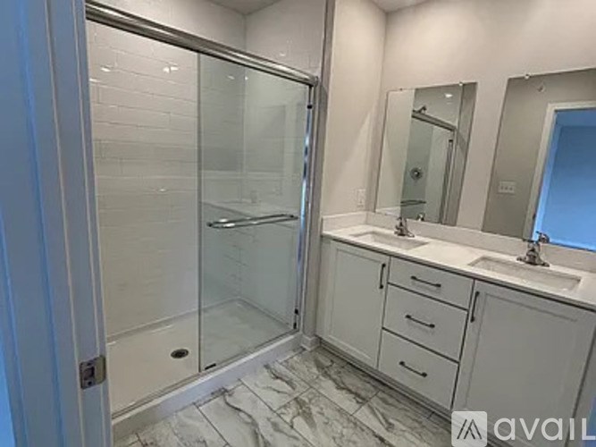 A bathroom with a walk-in shower, double sinks, and a large mirror.