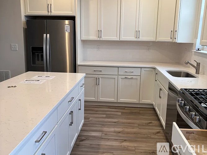 A kitchen with white cabinets and a stainless steel refrigerator.