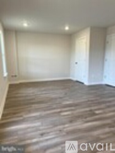 A room with wooden flooring and white walls.