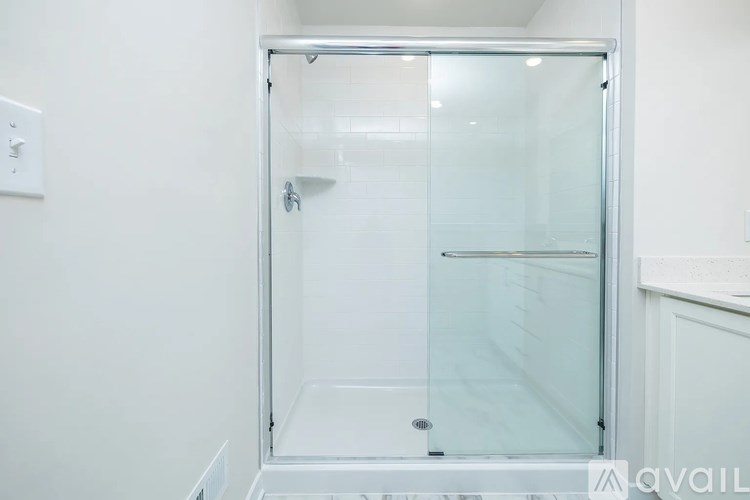 A glass shower stall with a white door and a white wall.