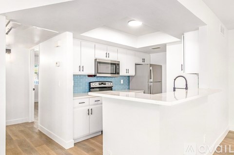 A kitchen with white cabinets and a blue backsplash.