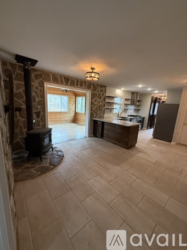A spacious living room with a stone fireplace and a television.