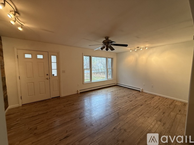 A spacious room with wooden flooring and a ceiling fan.