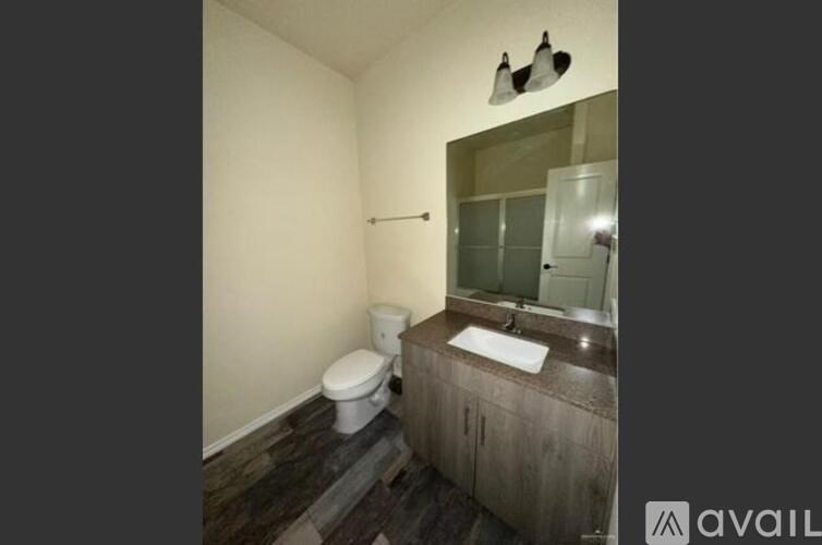 A bathroom with a toilet, sink, and mirror.