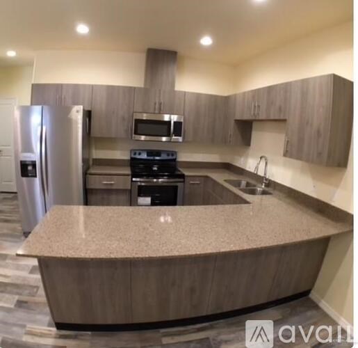 A kitchen with a refrigerator, microwave, oven, and sink.
