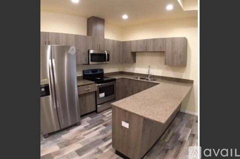 A kitchen with a refrigerator, microwave, oven and a counter top.
