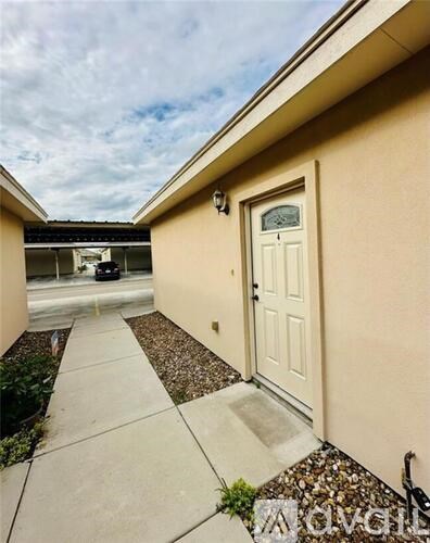 A white door is on the right side of a concrete walkway.