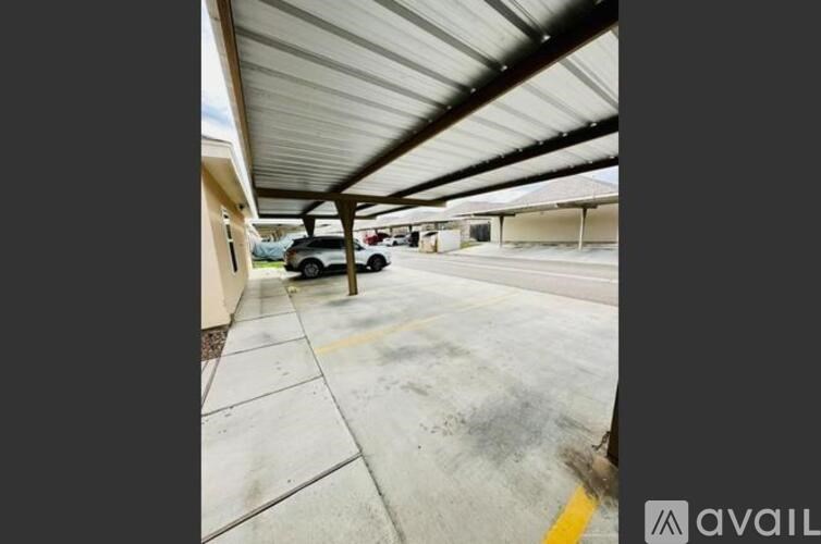 A parking lot with a car parked under a covered area.