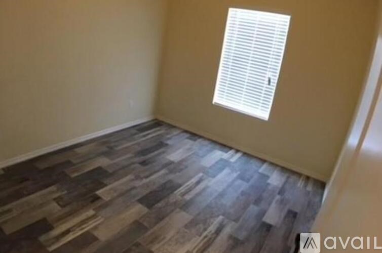 A room with a wooden floor and a window with blinds.