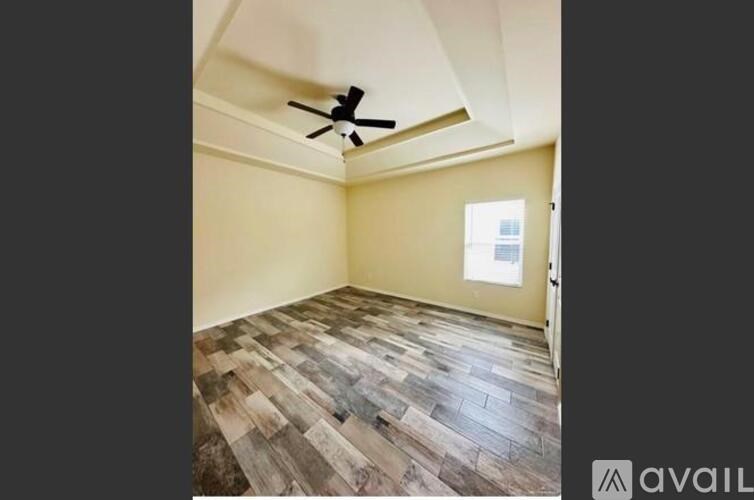 A room with a ceiling fan and wooden flooring.