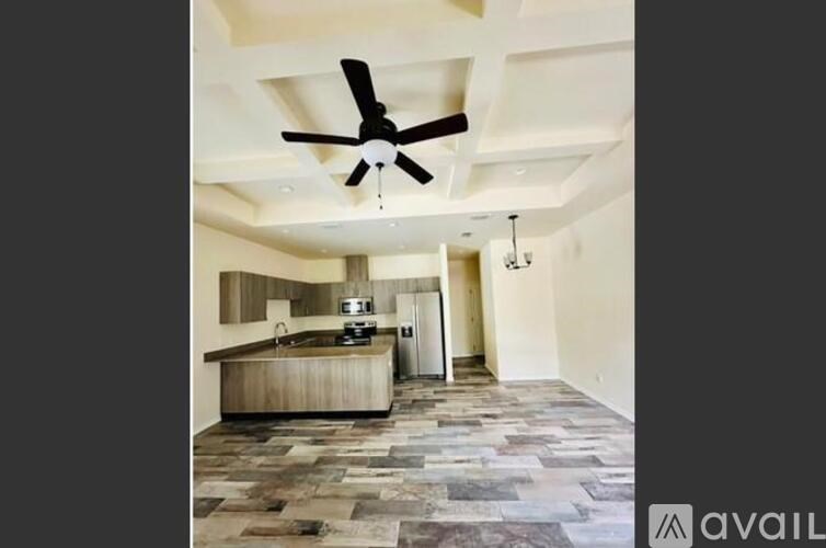 A modern kitchen with a ceiling fan and stone flooring.