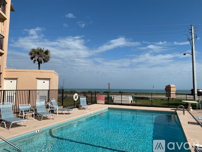 A pool with chairs and a palm tree in the background.