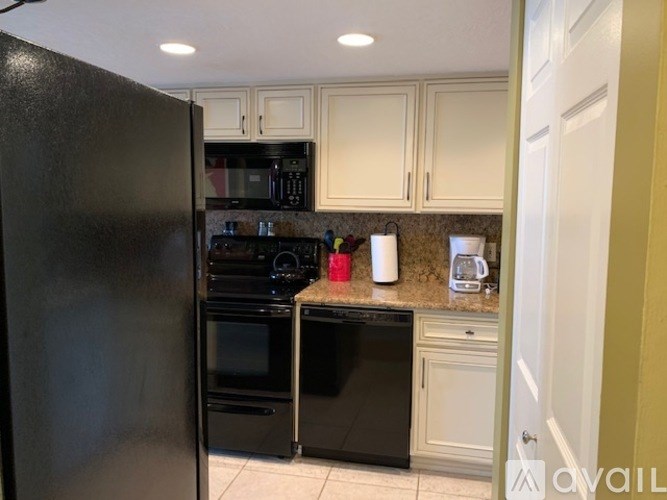 A kitchen with black appliances and white cabinets.