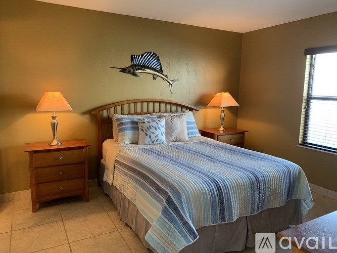 A bedroom with a bed, two lamps, and a wall decoration.