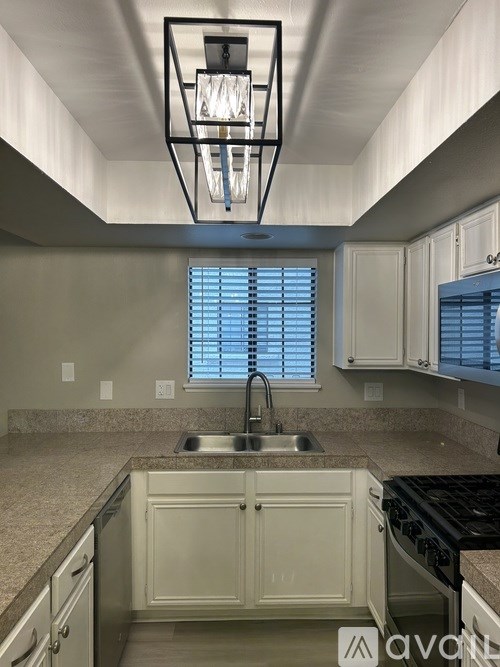 A kitchen with a sink, stove, and cabinets.