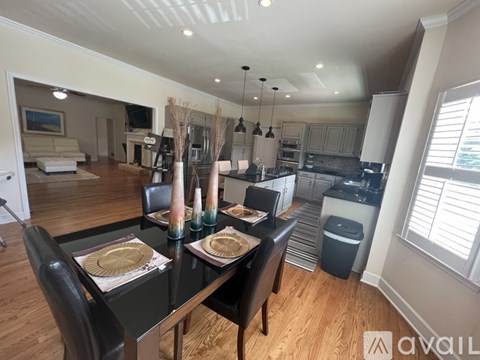 A dining room with a table set for two and a kitchen in the background.