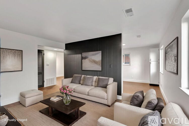 A living room with a white couch, a coffee table, and a painting on the wall.