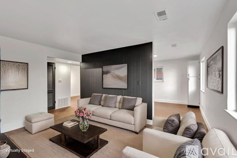 A living room with a white couch, a coffee table, and a painting on the wall.