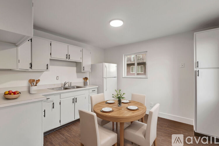 A kitchen with white cabinets and a wooden table with chairs.