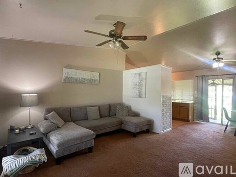 A living room with a grey couch and a ceiling fan.