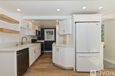 A kitchen with white cabinets and appliances.