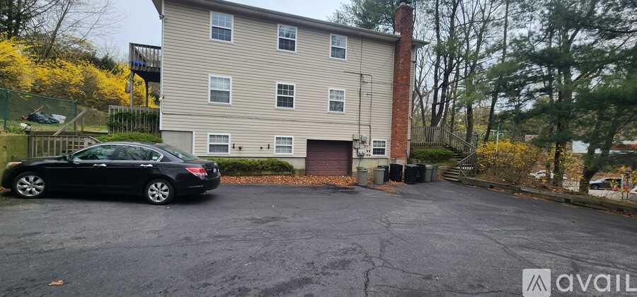 A black car is parked in a parking lot in front of a two-story building.