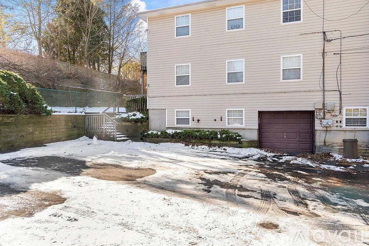 A building with a brown garage door is surrounded by a snowy landscape.