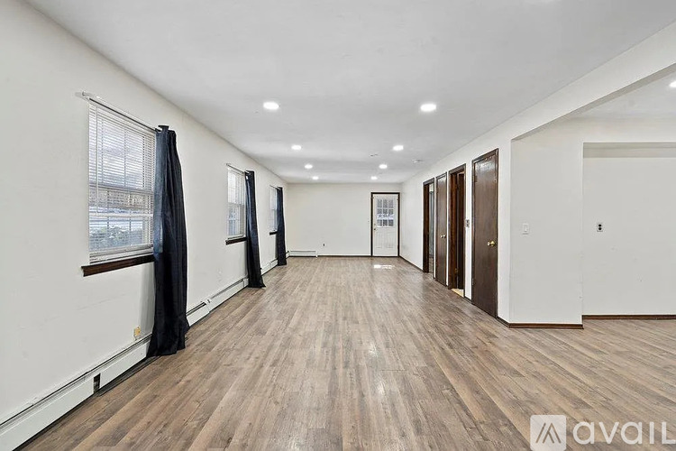 A spacious room with wooden flooring and white walls.