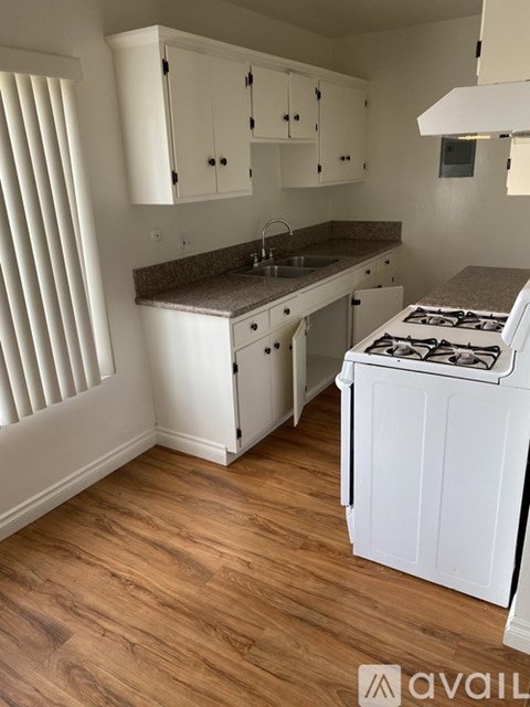 A kitchen with white cabinets and a white stove top oven.