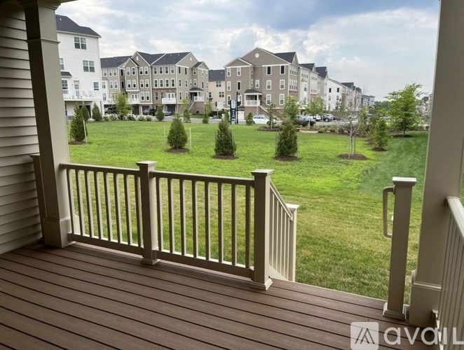 A view from a balcony overlooking a grassy area with trees and apartment buildings.