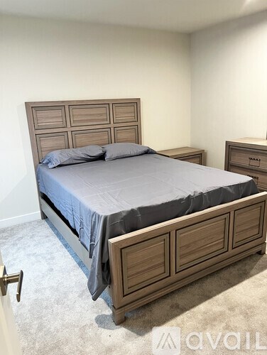 A bed with a wooden headboard and drawers underneath it in a room.