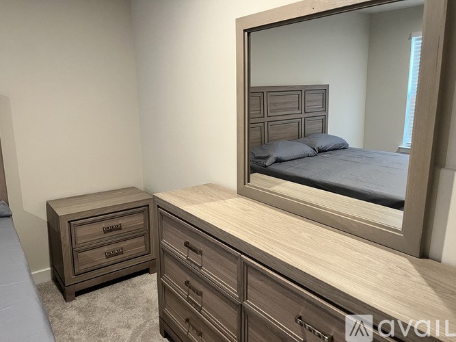 A bedroom with a bed, dresser, and mirror.