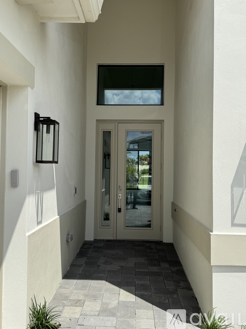 A modern house entrance with a glass door and a black lantern on the wall.