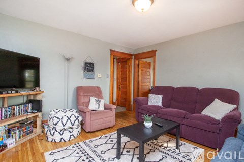 A living room with a purple couch and a black coffee table.