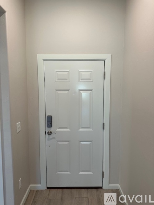 A white door with a handle and a lock is in a room with a wooden floor.