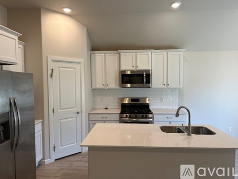 A kitchen with white cabinets and a stainless steel refrigerator.