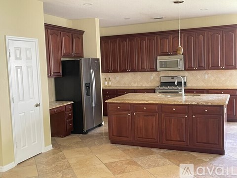 A kitchen with brown cabinets and a black refrigerator.