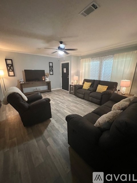 A living room with a black couch and a television.
