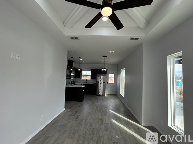 A spacious room with a ceiling fan and a large window.