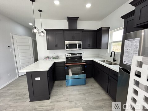 A modern kitchen with black cabinets and a white countertop.
