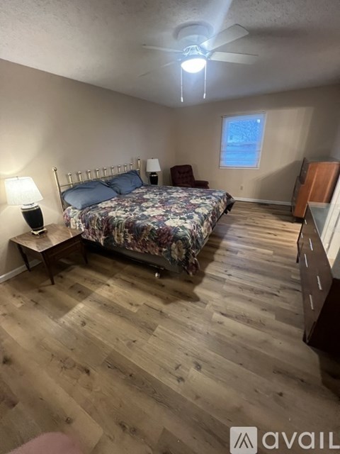 A bedroom with a bed, nightstand, and chair.